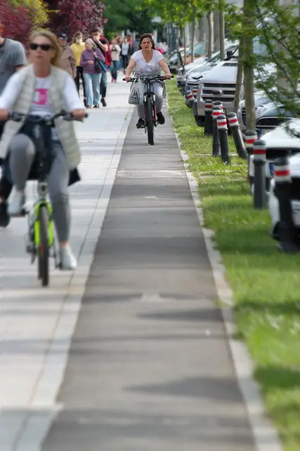 Woman riding her bike in densely populated are on the sidewalk