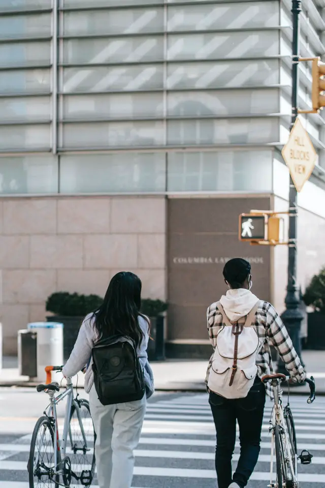 Woman and man walking bikes across a crosswalk in a city