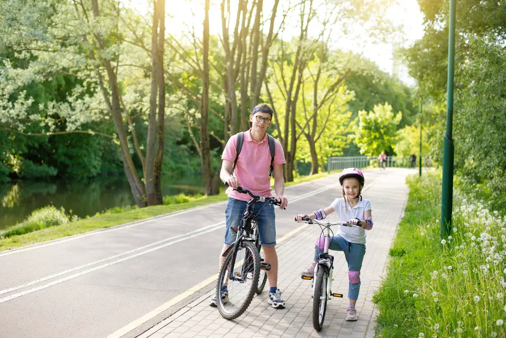 Little girl riding bikes with dad