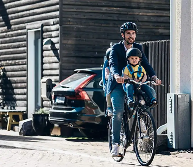 Man riding bike in chity with baby in child seat on the front and the back