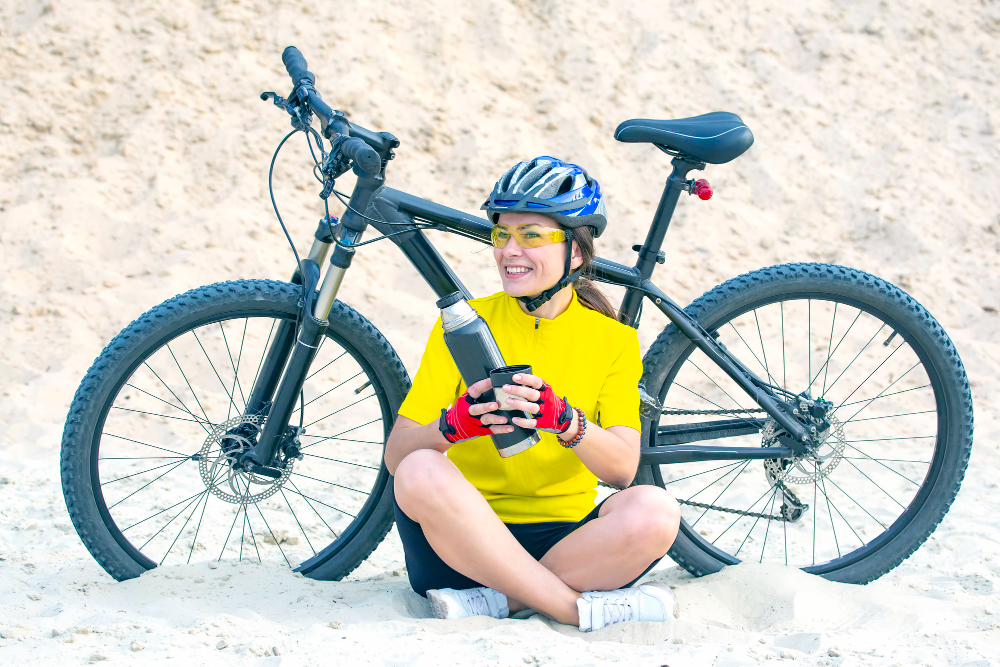 Women cyclist with electric bike on the sand