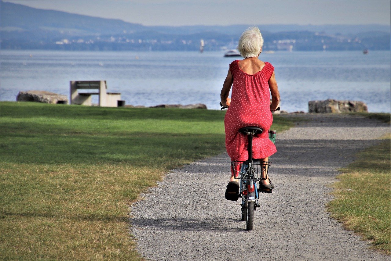 Senior woman in red dress riding an electric bike for fun.