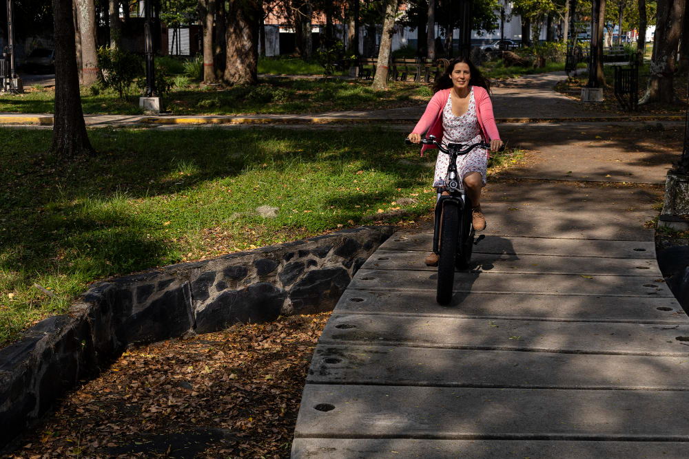 young woman latin american is riding her electric bicycle in park