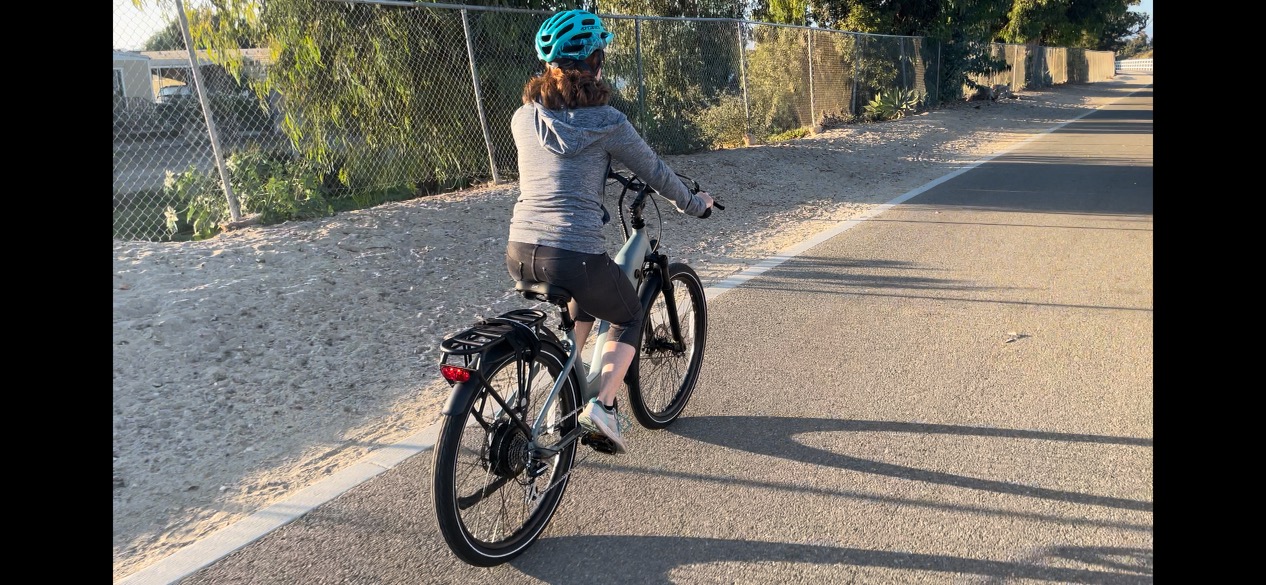 Woman riding away on Ride1Up 700 Step-Through Electric Bike