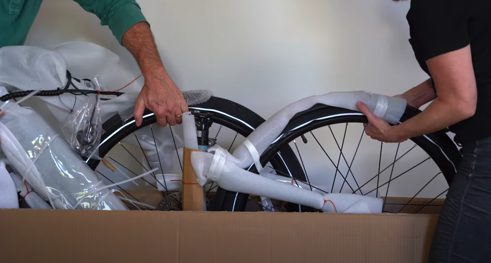 two people pulling electric bike out of box