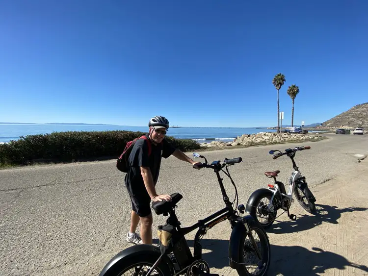 Man standing next to e-bike near the ocean