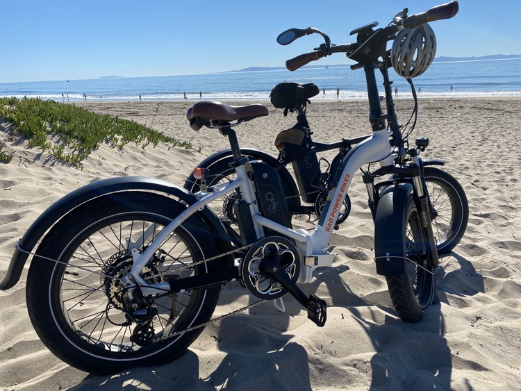 two e-bikes side-by-side on sand at the beach