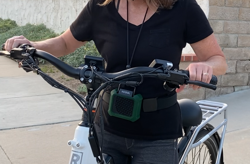 Woman wearing portable fan around neck on electric bike